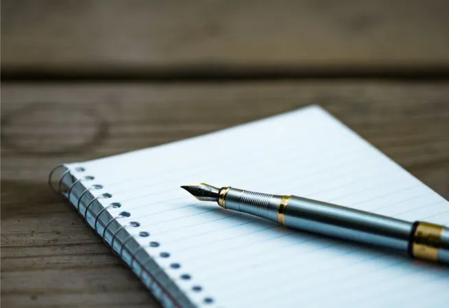 strategie-editoriale Un stylo-plume décapuchonné, posé sur un carnet à spirale blanc