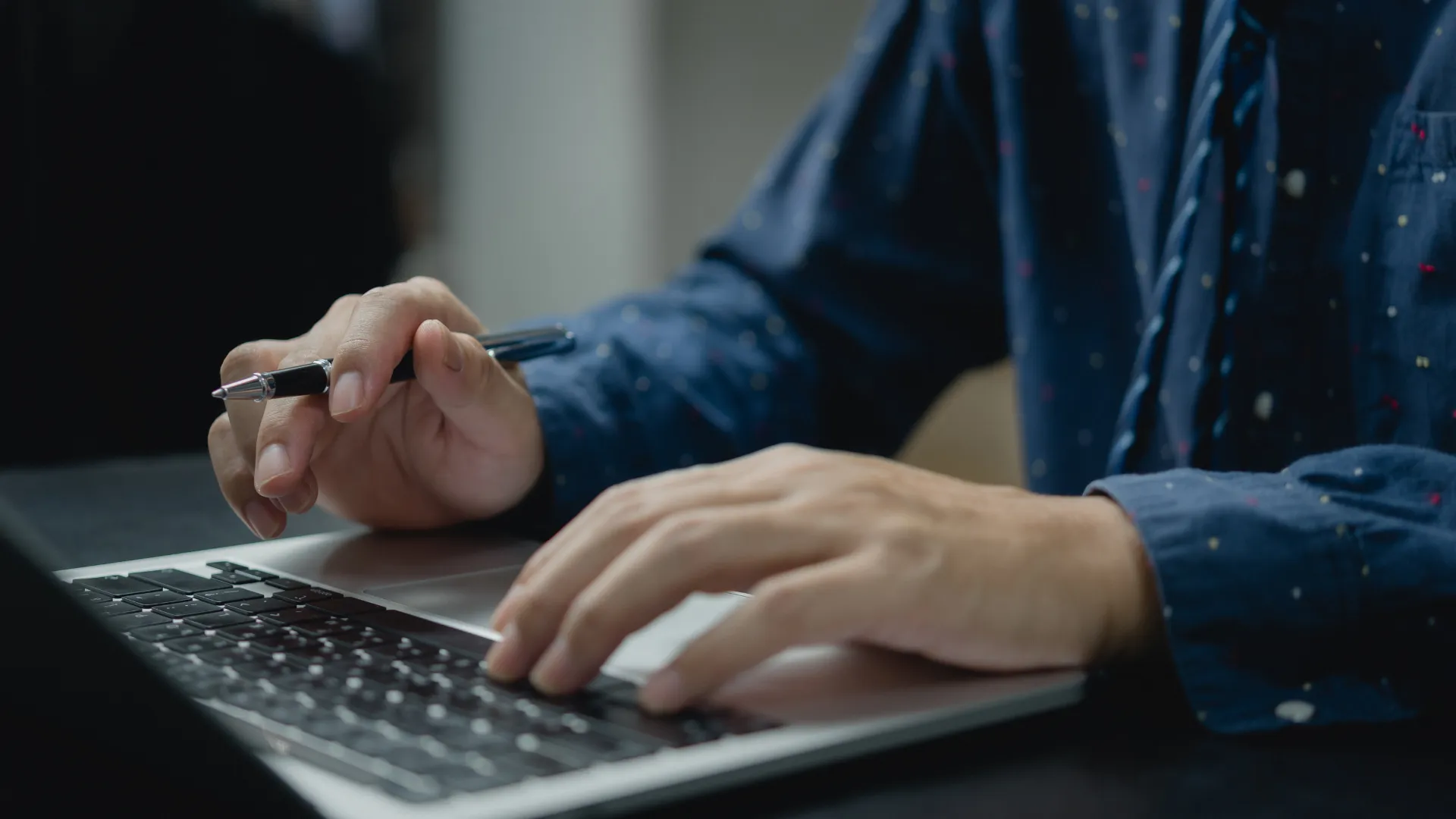 Image-article-exemples-transmedia Un homme écrit sur les touches de son clavier d'ordinateur un exemple transmédia, un stylo à la main.