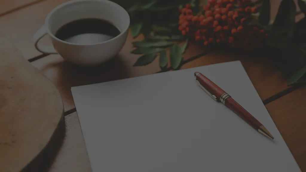 Un stylo est posé sur une feuille à côté d'un café, prêt à écrire une histoire.
