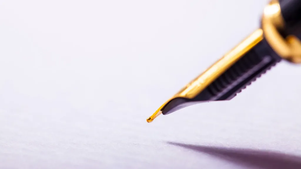 image-page-redaction-contenus-professionnels un stylo-plume s'apprête à écrire quelque chose sur du papier blanc après un accompagnement à la rédaction de contenus professionnels.